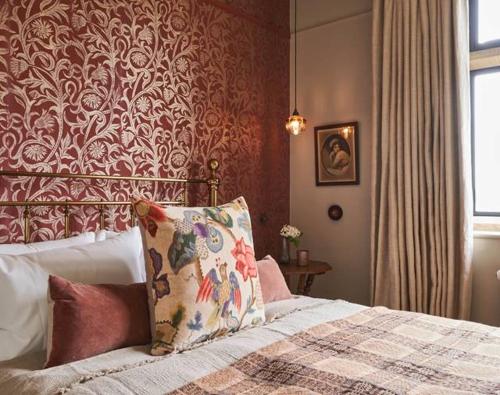 a bedroom with a bed with a red wall at The Lakes By YOO in Lechlade