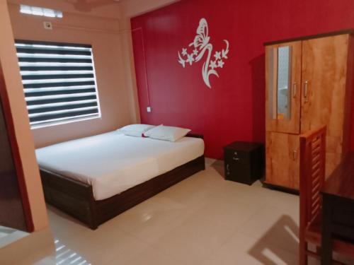 a bedroom with a bed and a red wall at KK Residency in Perintalmanna