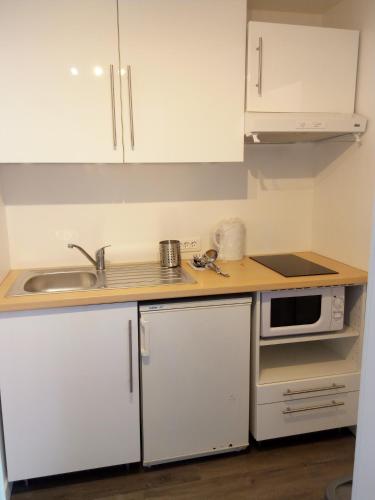La cuisine est équipée de placards blancs, d'un évier et d'un four micro-ondes. dans l'établissement Kerbugalic GR34, à Trévou-Tréguignec