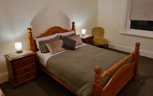 a bedroom with a wooden bed with pillows and a window at Charming 100 yr old cottage in the heart of Moonta in Moonta