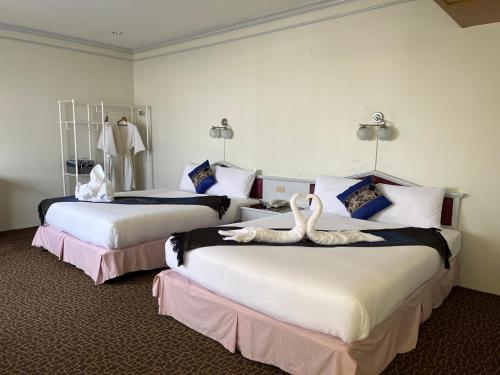 Merlin Grand Hotel في هات ياي: سريرين في غرفة الفندق عليها بجعة