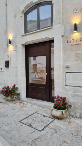 a front door of a building with two pots of flowers at LITHOS ROOMs in Matera