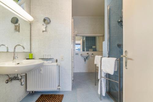 a white bathroom with a sink and a shower at Fuths Loft Penthouse 85 in Antwerp