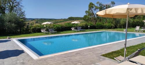 einen Pool mit einem Sonnenschirm, Stühlen und einem Tisch in der Unterkunft Agriturismo Santa Cristina in Gambassi Terme