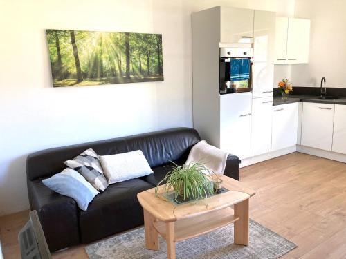 a living room with a black couch and a kitchen at Appartement Linde in Mürzzuschlag