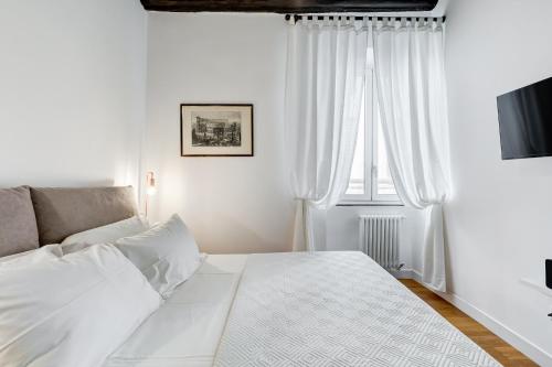 a white bedroom with a bed and a window at Boschetto 118 in Rome