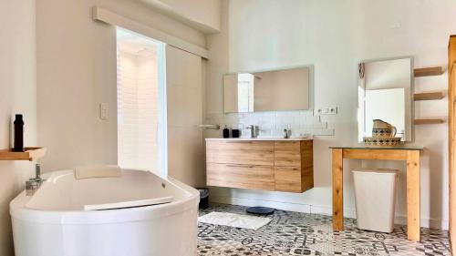 ein weißes Badezimmer mit einer Badewanne und einem Waschbecken in der Unterkunft L'atelier Insolite - Piscine chauffée in Montauban