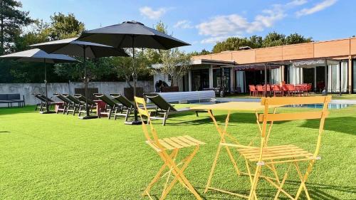 a group of chairs and a table with an umbrella at L'atelier Insolite - Piscine chauffée in Montauban