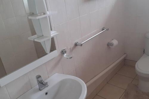 a white bathroom with a toilet and a sink at Spacious Executive Holiday Apartment In Bulawayo in Bulawayo