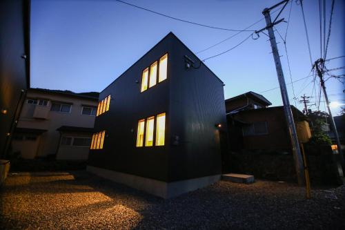 a black house with lit windows on the side of it at PrimeRoom Beppu Suite in Beppu