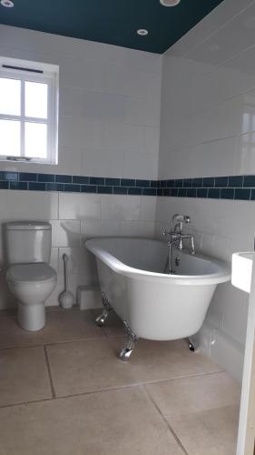 a white bathroom with a tub and a toilet at The Annex at Oliver Farm in York