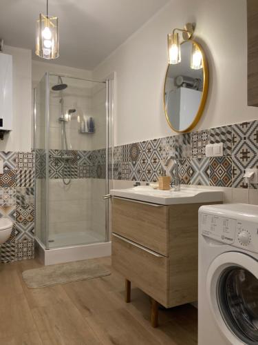 a bathroom with a shower and a washing machine at Uroczy Apartament u Mirki in Podgórzyn