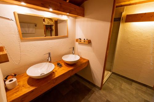 a bathroom with two sinks and a mirror at Hotel Restaurant Les Lilas in Les Diablerets