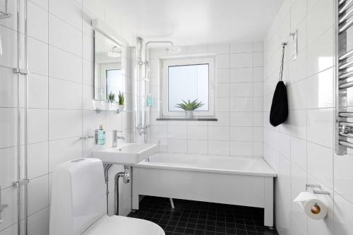 a white bathroom with a tub and a sink and a toilet at Best Western Princess Hotel in Norrköping
