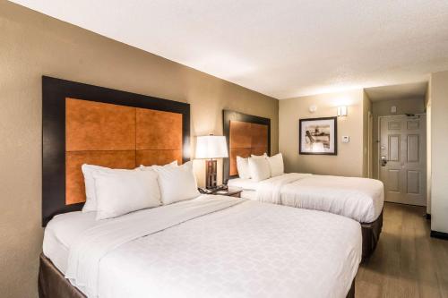 a hotel room with two beds with white sheets at Quality Inn in Pensacola