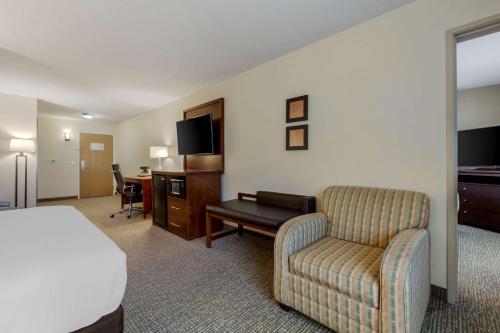 a hotel room with a bed and a chair at Comfort Suites Johnson Creek Conference Center in Johnson Creek