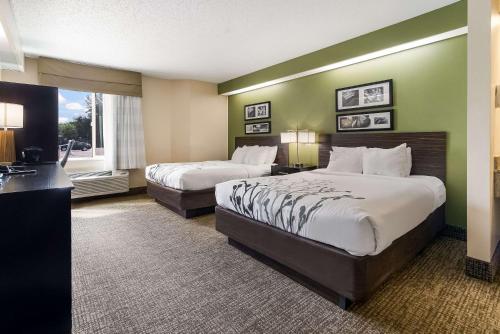 a hotel room with two beds and a desk at Sleep Inn Airport in Sioux Falls