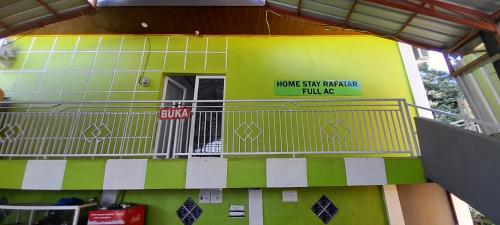 un edificio con un balcón con un cartel. en Homestay Rafatar, en Rantaupanjang