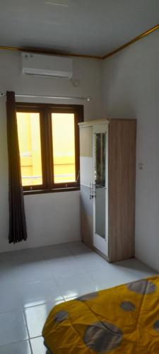 ein leeres Zimmer mit einem Kühlschrank und einem Fenster in der Unterkunft Homestay Rafatar in Rantaupanjang