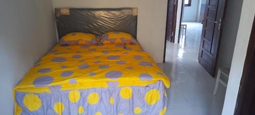 Bett mit gelber und blauer Decke in einem Zimmer in der Unterkunft Homestay Rafatar in Rantaupanjang