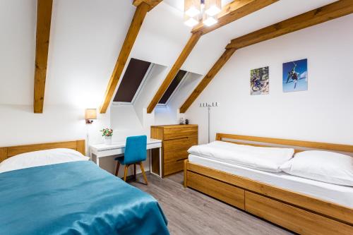 sypialnia z 2 łóżkami i biurkiem z niebieskim krzesłem w obiekcie Ski Chalet Klínovec w mieście Loučná pod Klínovcem