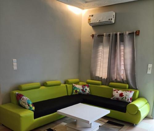a living room with a green couch and a table at Residence MaryHouse - Free Breakfast and Taxi From Airport in Cotonou