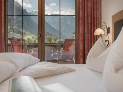 a bedroom with a bed and a large window at Hotel Garni Larcherhof in Mayrhofen