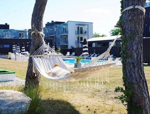 eine Hängematte, die von zwei Bäumen neben einem Pool hängt in der Unterkunft First Hotel Kokoloko in Visby