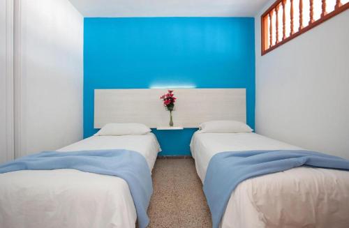 two beds in a room with a blue wall at Apartamentos Europa in Maspalomas