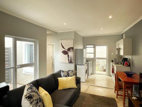 uma sala de estar com um sofá preto e uma cozinha em Alon Cottage em Joanesburgo