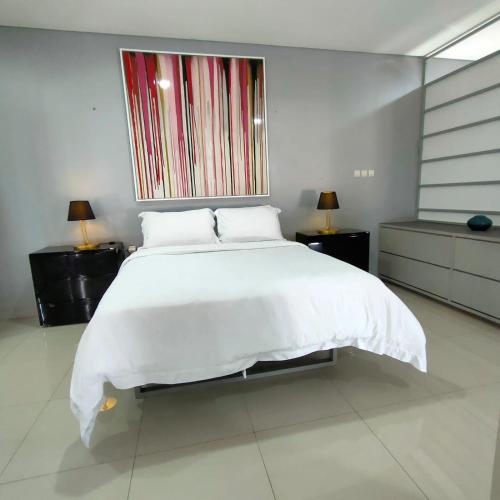 Un dormitorio con una gran cama blanca y una ventana. en Suite Room Gezonder Antapani, en Bandung