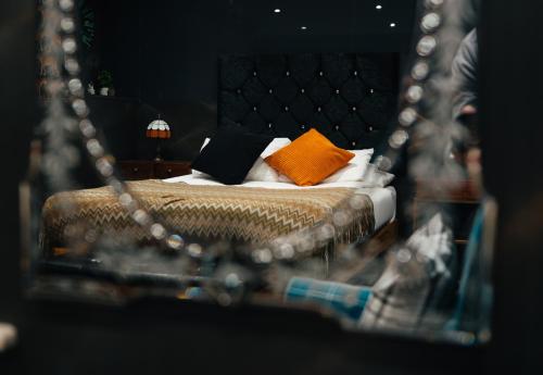 a reflection of a bed with orange and black pillows at The Rokxy Townhouse & Residences - Kings Cross in London