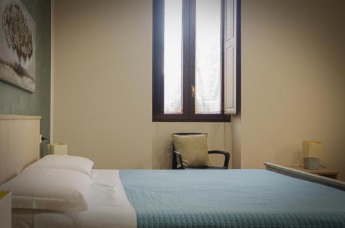 a bedroom with a bed and a chair and a window at La casa di Bice in Cassibile