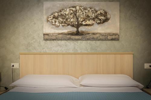 a bedroom with a bed with a tree on the wall at La casa di Bice in Cassibile