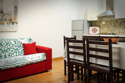a living room with a red couch and a kitchen at La casa di Bice in Cassibile