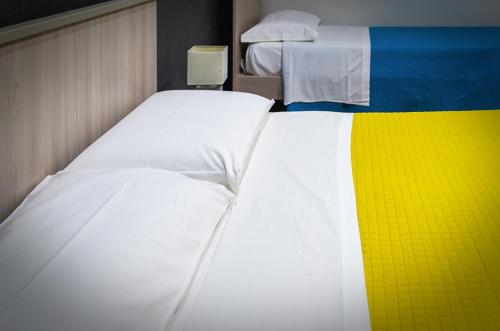 a bedroom with two white beds and a yellow and blue at La casa di Bice in Cassibile