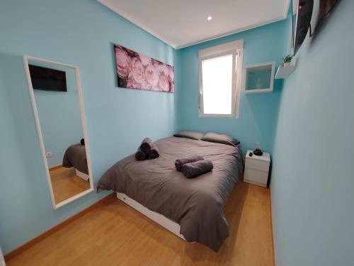 1 dormitorio con paredes azules y 1 cama con espejo en Apartamento Manuel Becerra, en Madrid