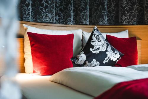 a bed with red and white pillows on it at Ritzenhof - 4 Sterne Superior Hotel & Spa am See in Saalfelden am Steinernen Meer