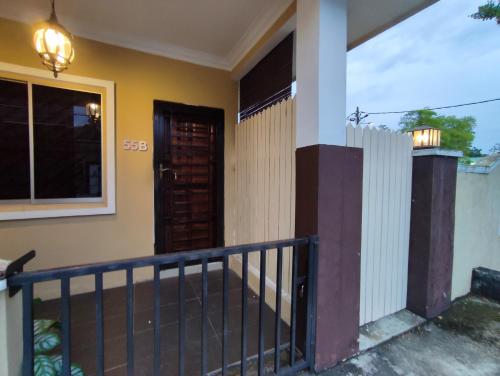 a house with a balcony with a door and a fence at Mini Green Homestay in Kulai