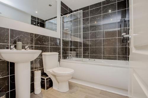 a bathroom with a toilet and a tub and a sink at 52 Molyneux Place - 5 Bedroom House in Peterborough Ideal for Groups and Families in Peterborough