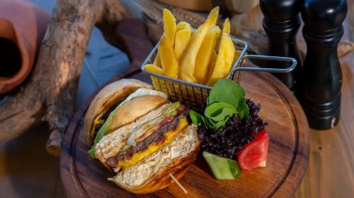 a sandwich and french fries on a wooden plate at Azka Hotel in Bodrum City