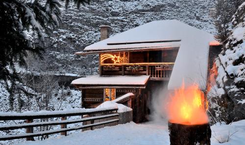 a log cabin with a fire in the snow at Naturhotel Hüttenwirt im Grossarltal in Hüttschlag