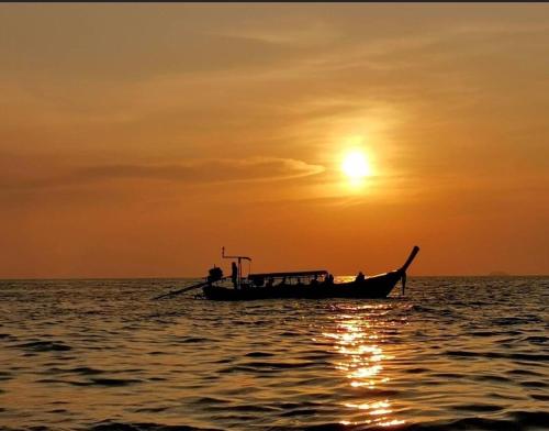 a boat in the ocean with the sunset in the background at PP Midnight Hotel in Phi Phi Don