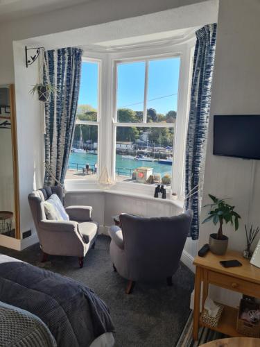 a bedroom with a bed and two chairs and a window at The Ocean Guesthouse in Weymouth