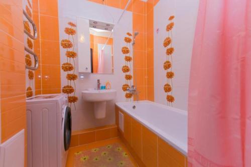 La salle de bains est pourvue de carrelage orange, d'un lavabo, d'une baignoire et de toilettes. dans l'établissement Warm apartment, à Affligem