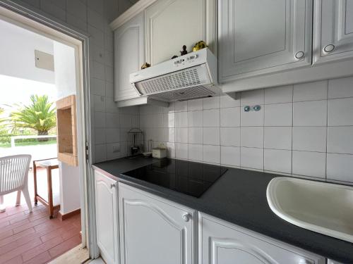 a kitchen with white cabinets and a black counter top at Vilamoura Typical 1 With Pool by Homing in Vilamoura