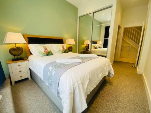 een slaapkamer met een groot wit bed en een spiegel bij Quayside Apartment - Large and Spacious Duplex in Castletown
