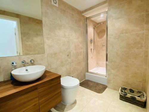 Un baño con lavabo, inodoro y ducha. en Quayside Apartment - Large and Spacious Duplex, en Castletown