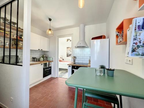 a kitchen with a green table and a refrigerator at Studio LE VINTAGE - Maison 1911 - confort & prestige in Gien