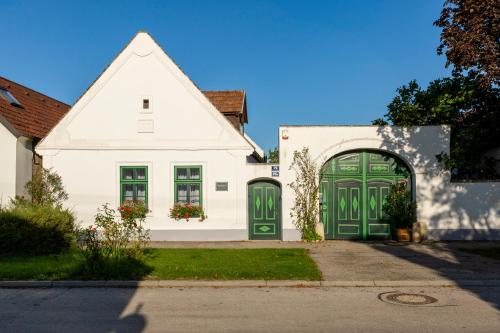 a white house with green doors on a street at Weissenbacherhof B&B in Oslip